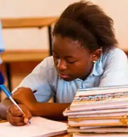 Photo of a Schoolgirl Writing in a Classroom