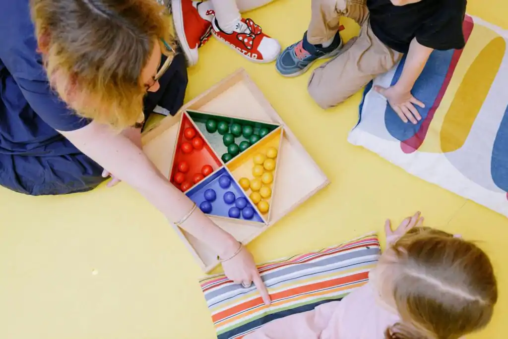 Teacher Sitting on Floor with Kids Pointing on colours